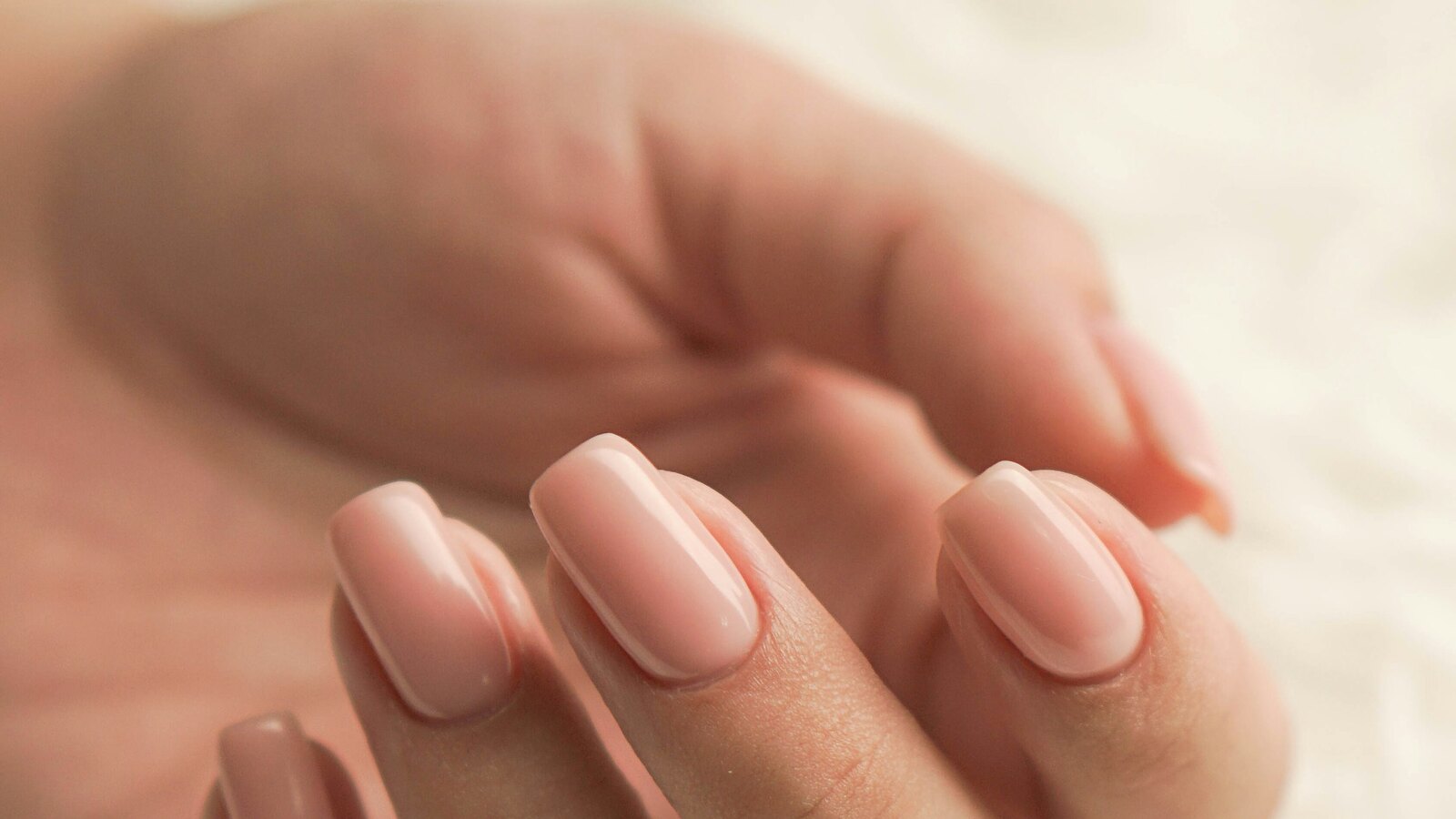A close up of a clean, neutral manicure